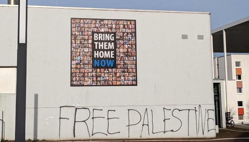 Hauswand mit einem Plakat der israelischen Geiseln und dem Graffiti "Free Palestine" darunter